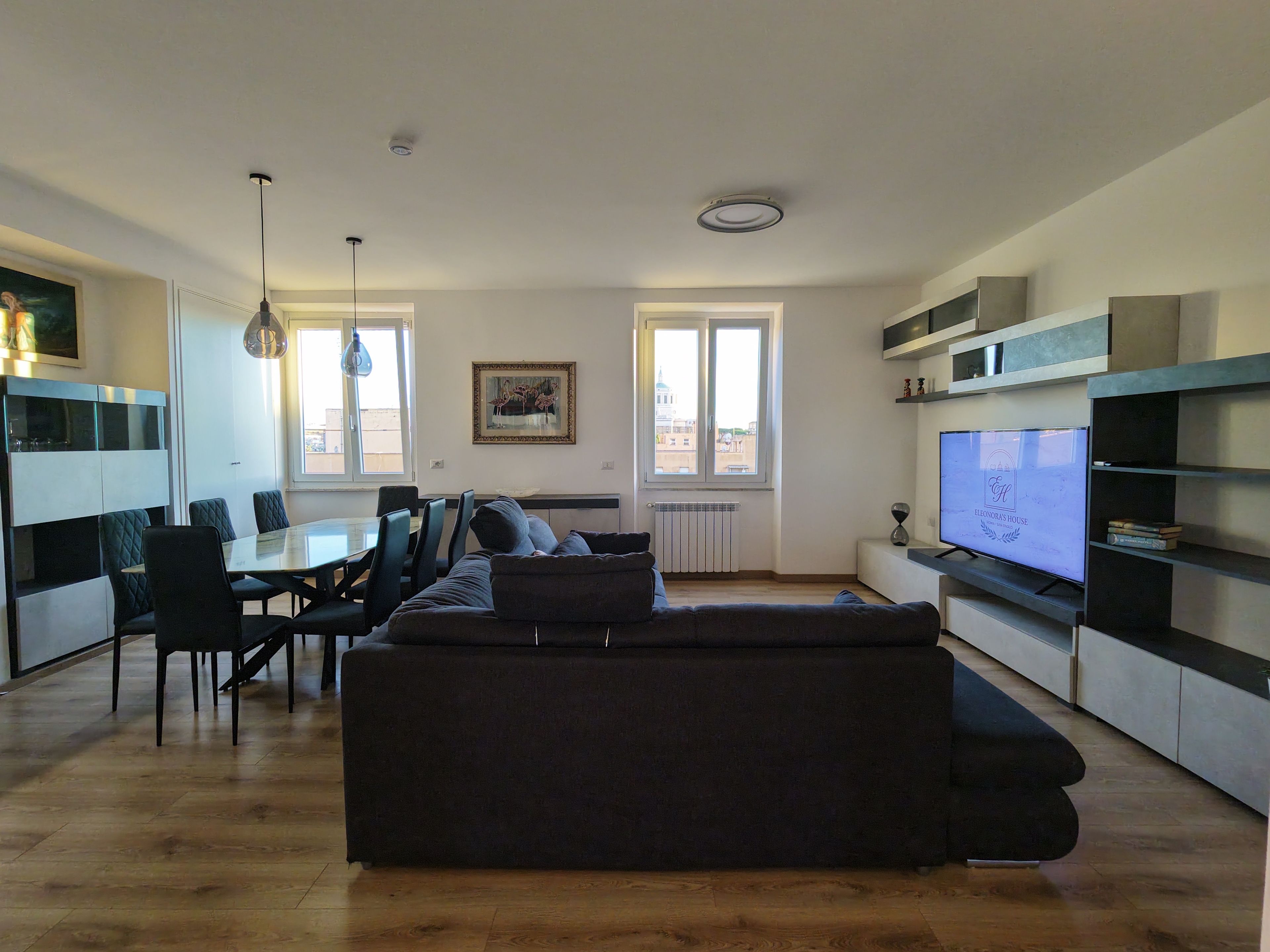 Un salon moderne comprenant un canapé, une table à manger, des chaises et un téléviseur.