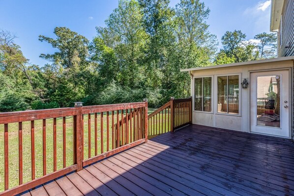 A wooden deck with a glass door leading to a covered area, surrounded by trees. - Exmoor Sunroom Retreat - 2Story Home (Jacksonville)