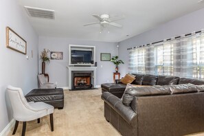A living room with a fireplace, a sofa, a chair, and a television. - Exmoor Sunroom Retreat - 2Story Home (Jacksonville)