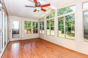 A spacious room with large windows, a ceiling fan, and a wooden floor. - Exmoor Sunroom Retreat - 2Story Home (Jacksonville)