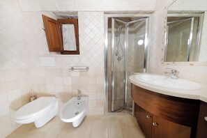 A bathroom with a toilet, bidet, sink, and glass shower enclosure. - New Listing (Puglia)