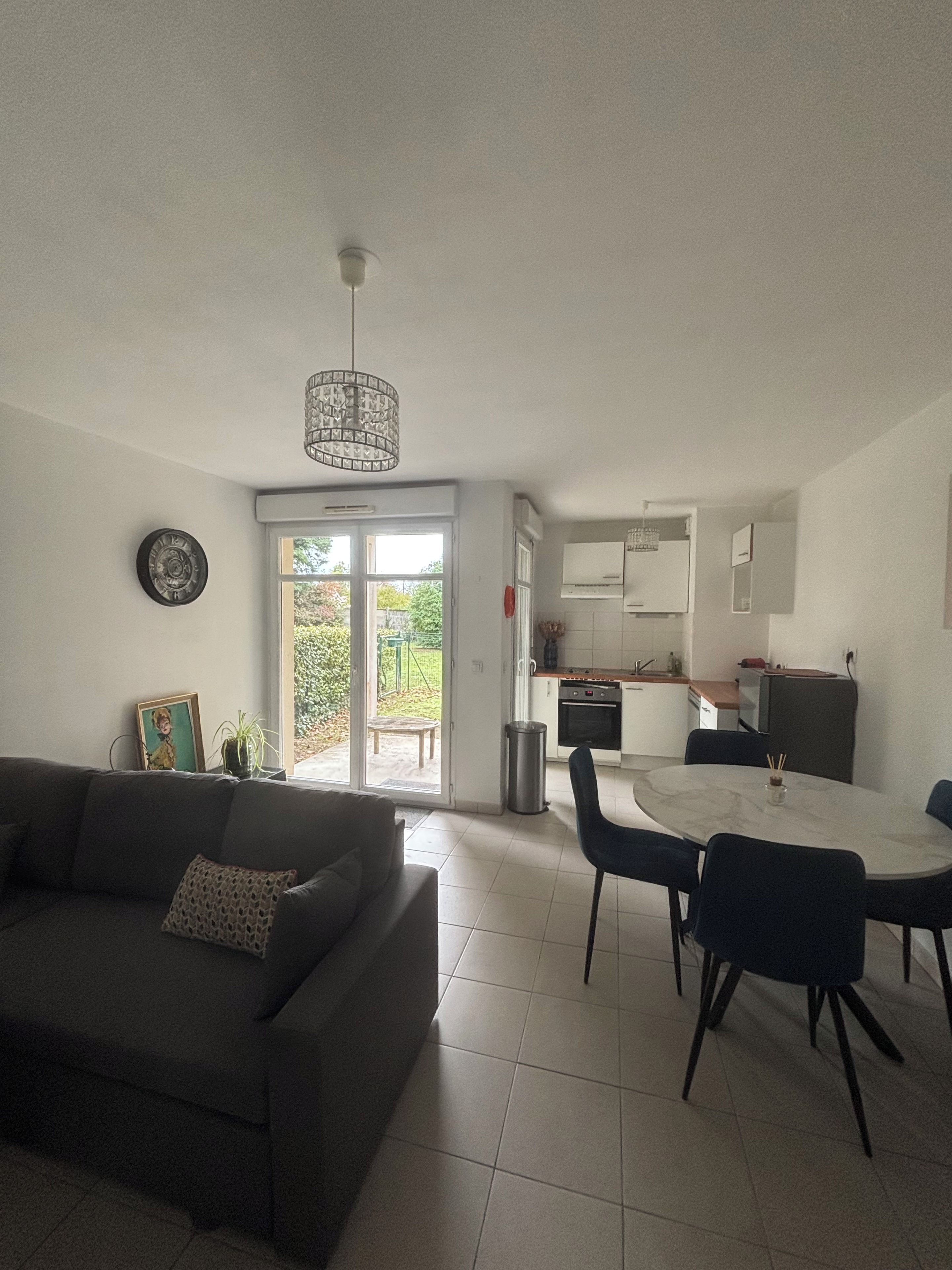 En stue med sofa, spisebord med stole, et køkken med skabe og en skydedør til en patio.