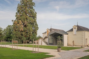 Un bâtiment à l’architecture moderne, un grand arbre au premier plan et une pelouse bien entretenue.