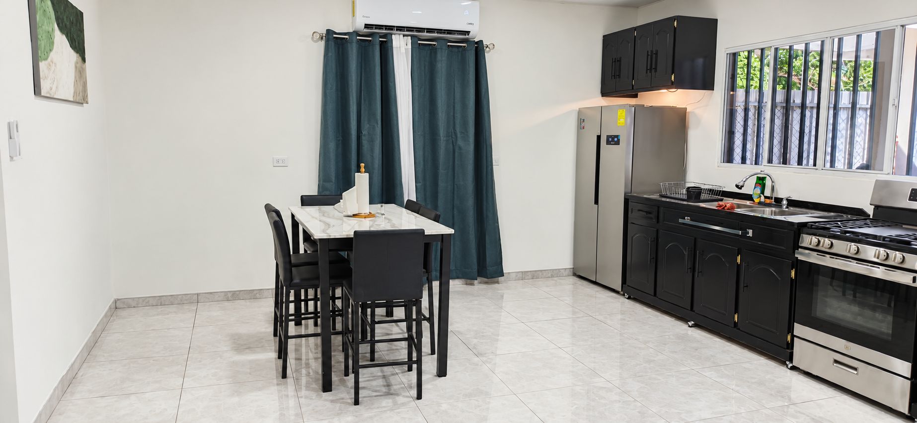 A kitchen with a dining table, chairs, a refrigerator, cabinets, and a stove.