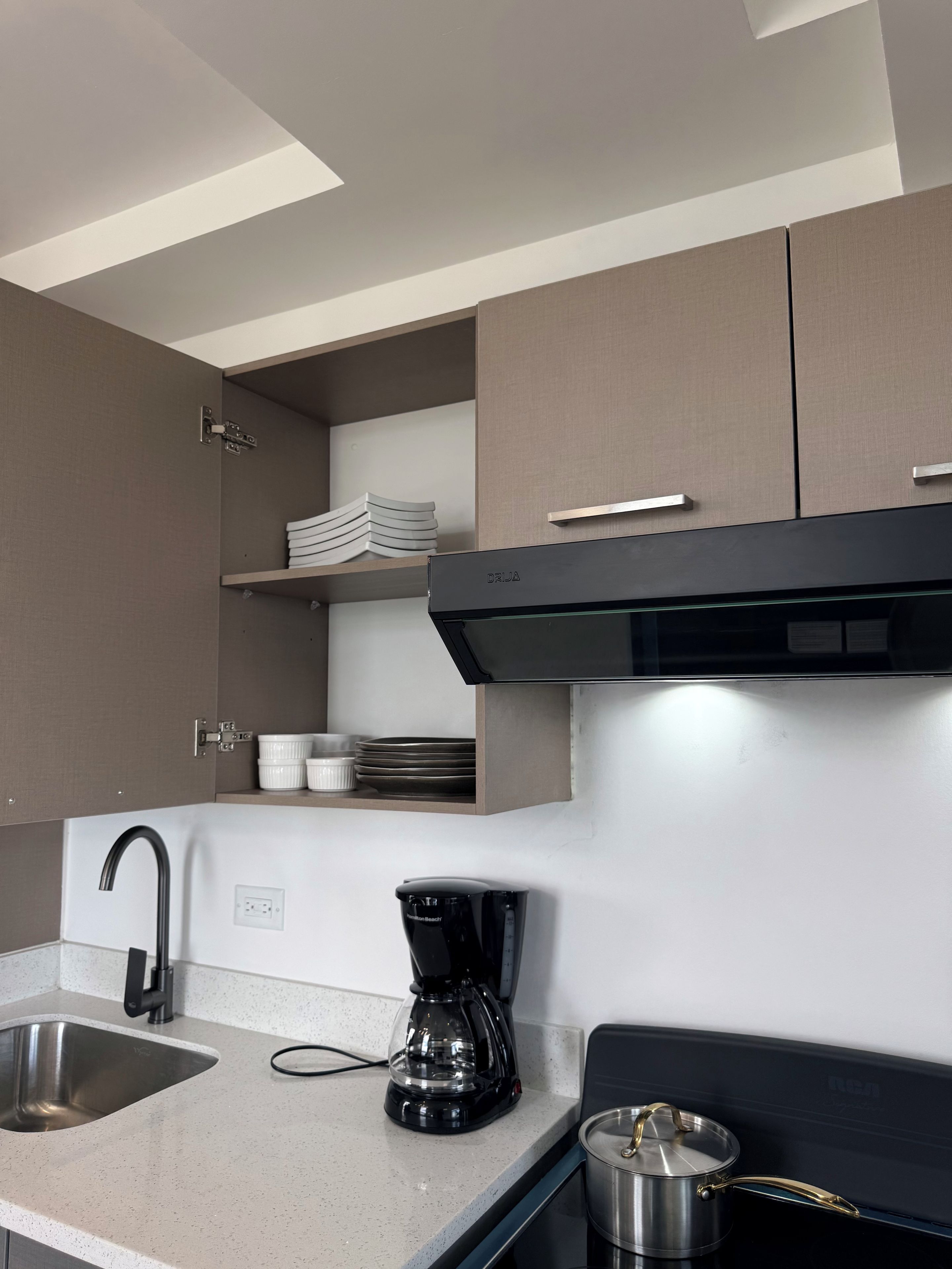 A modern kitchen with a built-in oven, a coffee maker, and a pot on the stove.