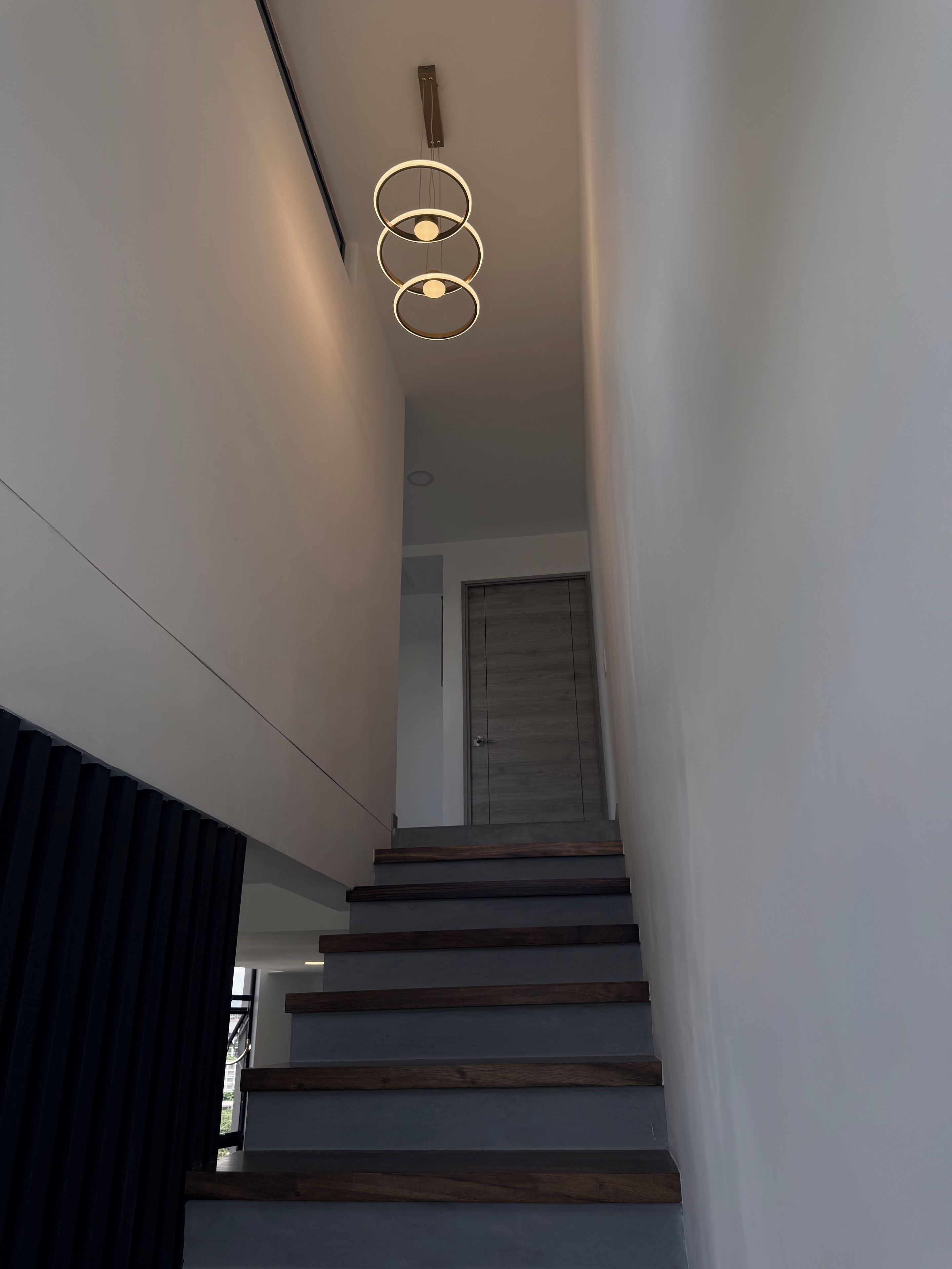 A staircase with wooden steps and a modern light fixture above.