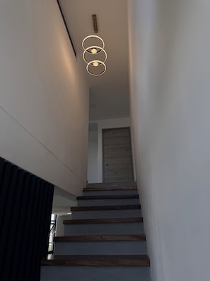 Una escala amb graons de fusta i un lluminari modern a la part superior.