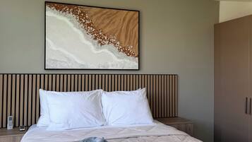 A hotel room with a bed, a wall-mounted artwork, a wardrobe, and a bedside table with a phone.