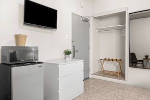 Habitación de hotel con kitchenette, televisión de pantalla plana, armario y una pequeña zona de estar.