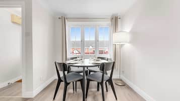 A dining area with a round table, four chairs, and a floor lamp.