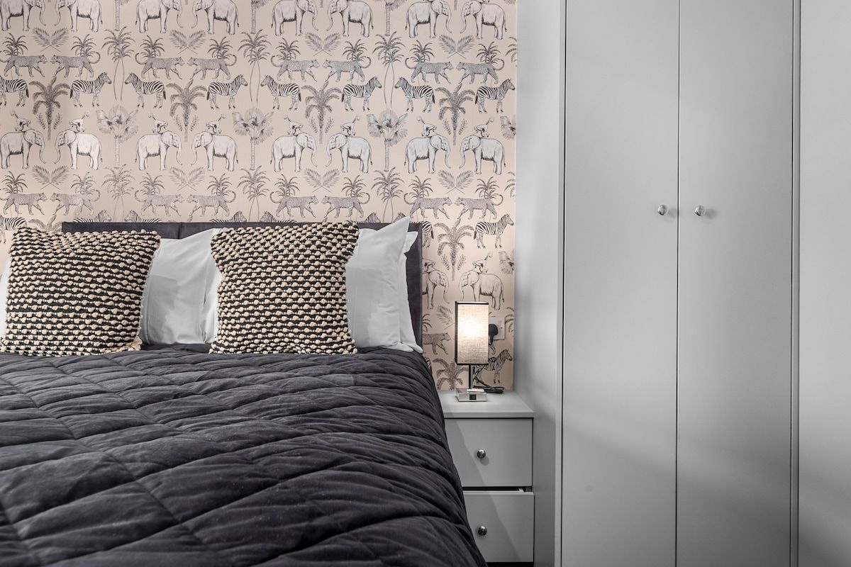 Un lit avec une tête de lit décorée, une lampe de chevet et une table de chevet dotée d’un tiroir.