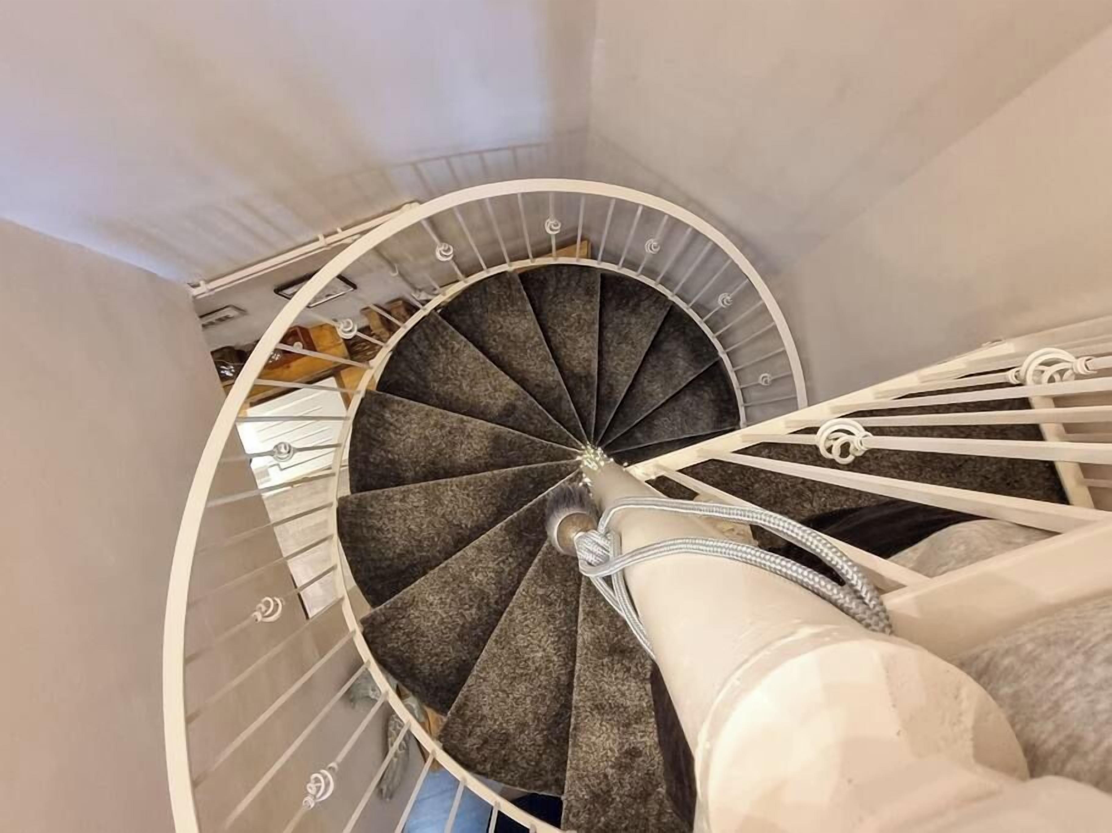 Een wenteltrap met een leuning en een ronde balustrade.