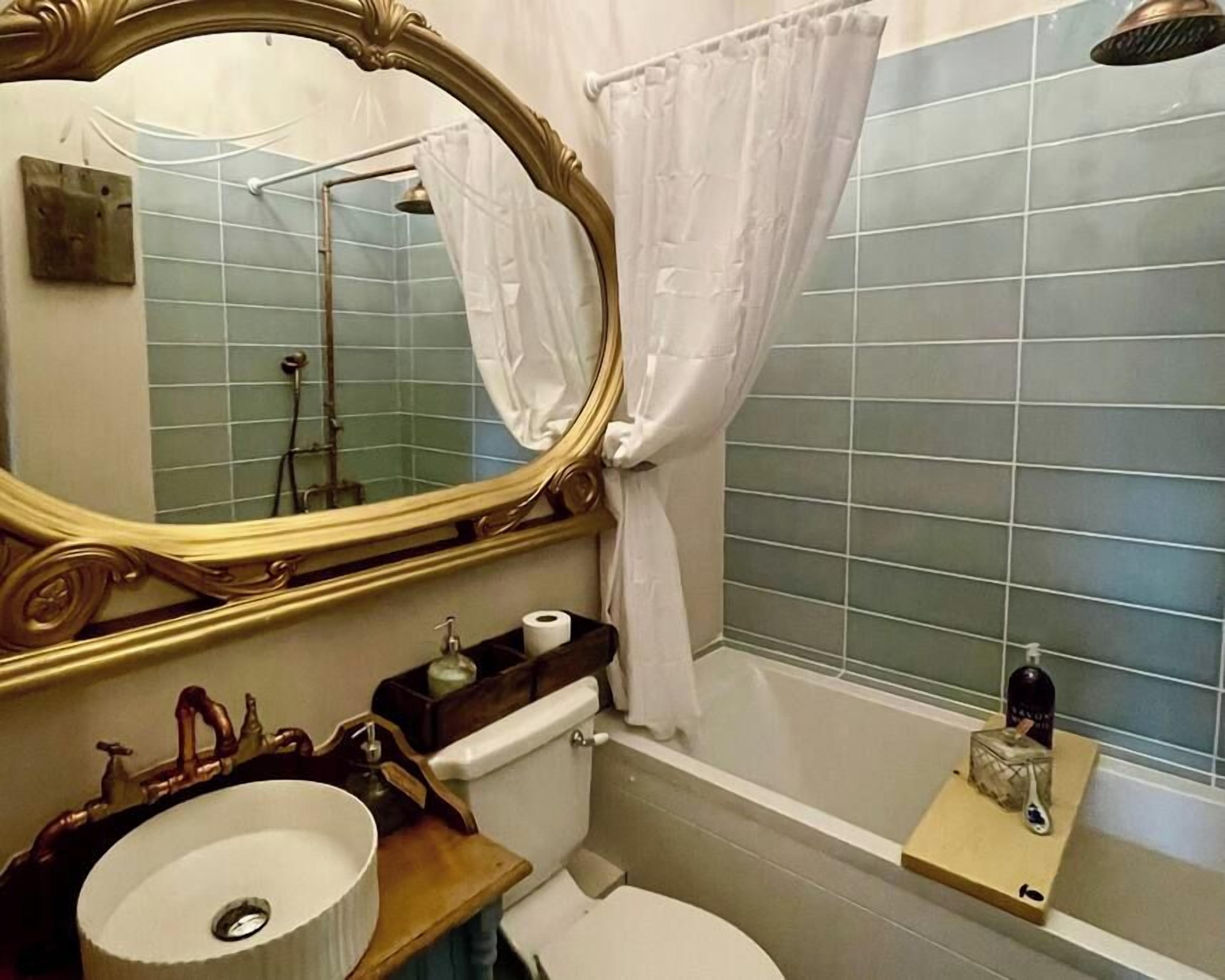 Casa de banho com um espelho grande, uma pia, sanita e banheira.