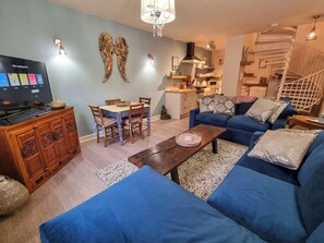 Sala de estar com televisão, sofá e área de refeições.