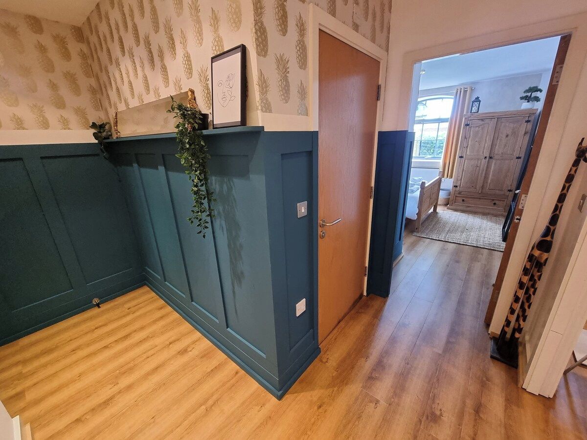 Ein Korridor mit Holzboden, einer blauen Tür und einer Pflanze an der Wand.