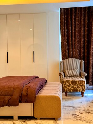 Ein Schlafzimmer mit Bett, einer Bank, einem Sessel und einem Kleiderschrank.