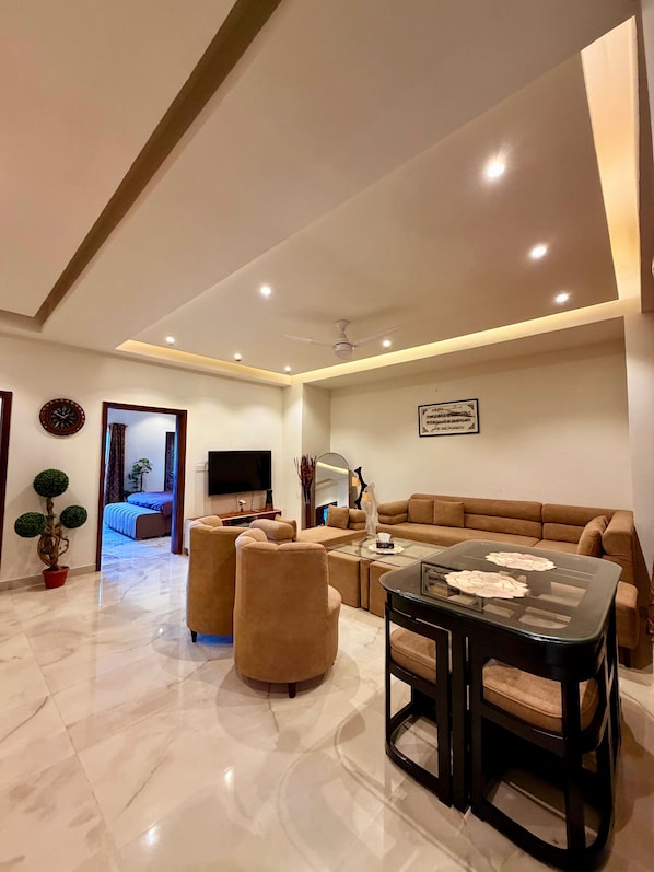 A modern living room with a sofa, armchairs, a coffee table, and a TV.