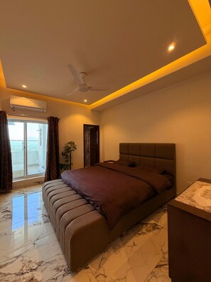A bedroom with a bed, a ceiling fan, a window with curtains, and a marble floor.