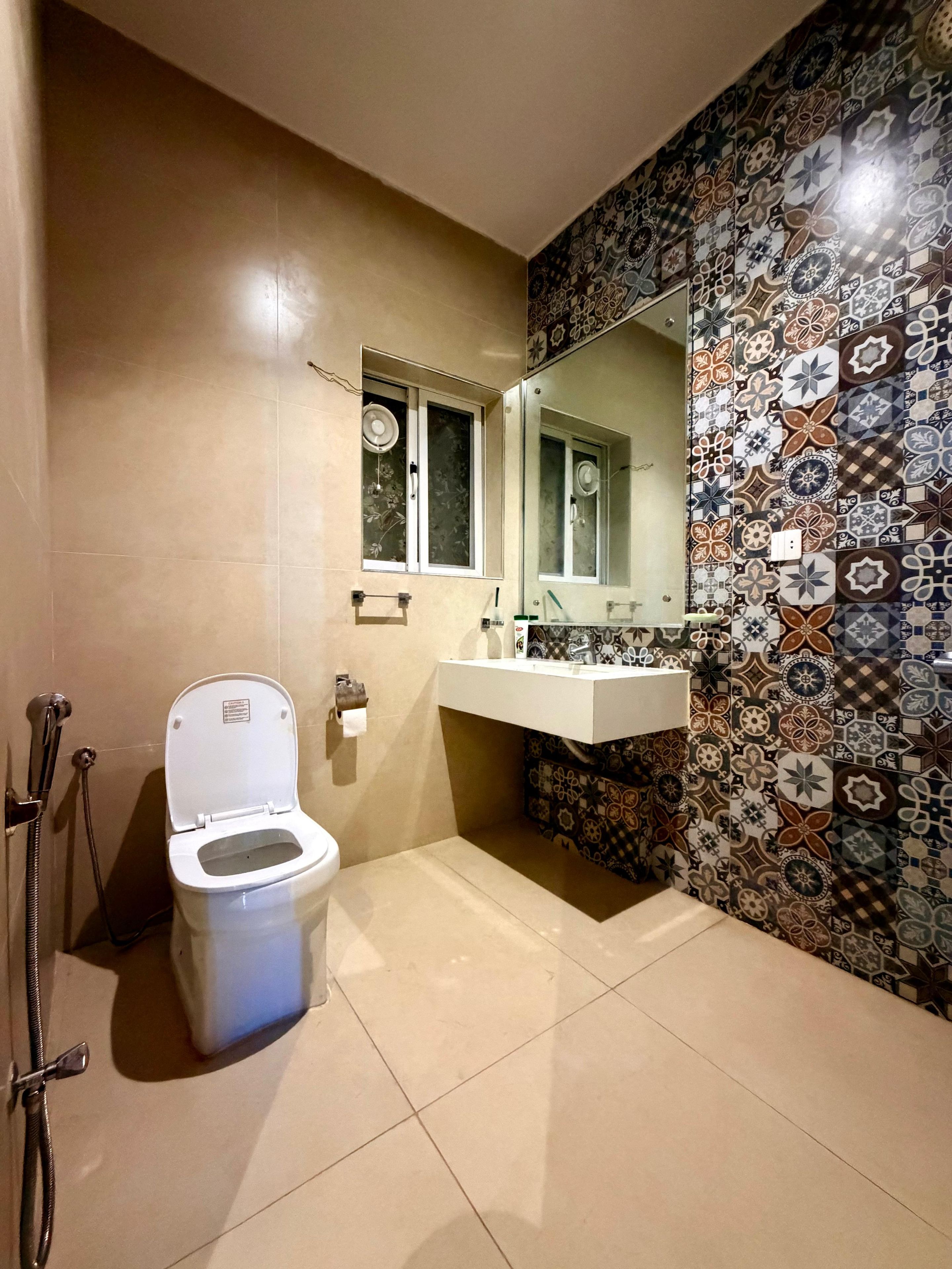 A bathroom with a toilet, a sink, a mirror, and a shower.