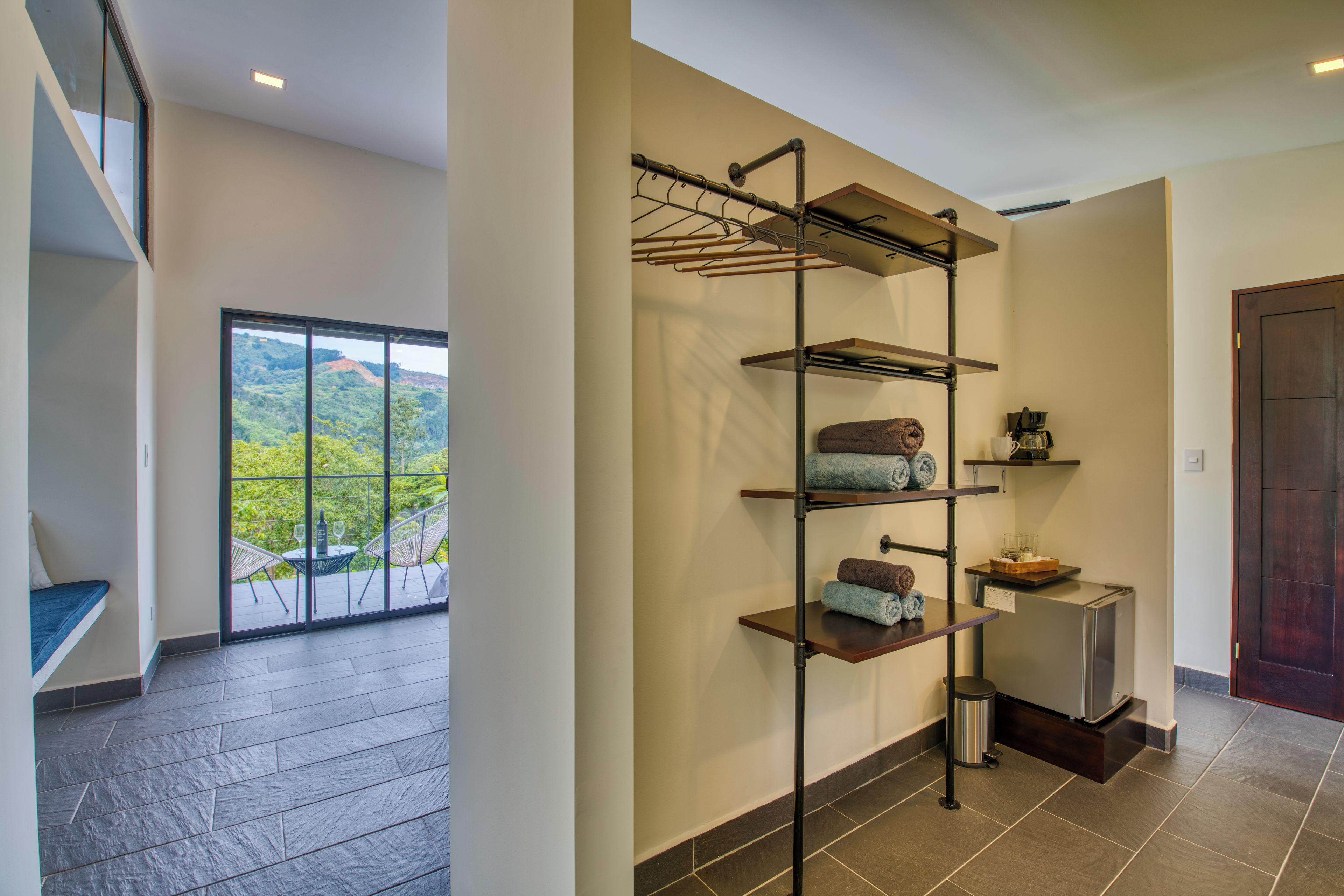 A modern interior with a built-in shelf unit holding towels, a coffee maker, and a trash bin.