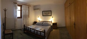 A bedroom with a wooden bed, bedside tables, a radiator, a chair, and a wardrobe.