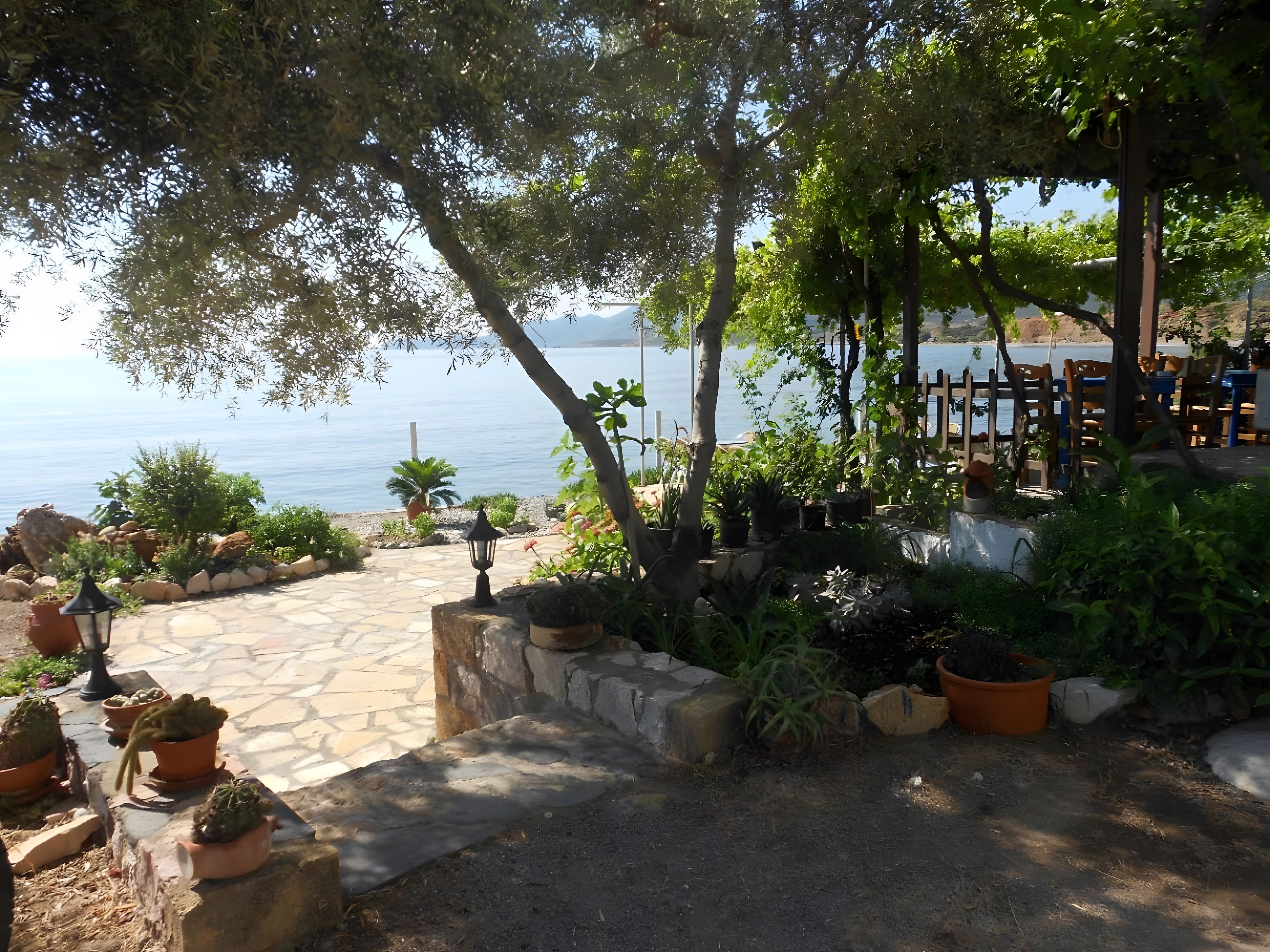 En patio med plantekasser, en sti af sten og udsigt til havet.