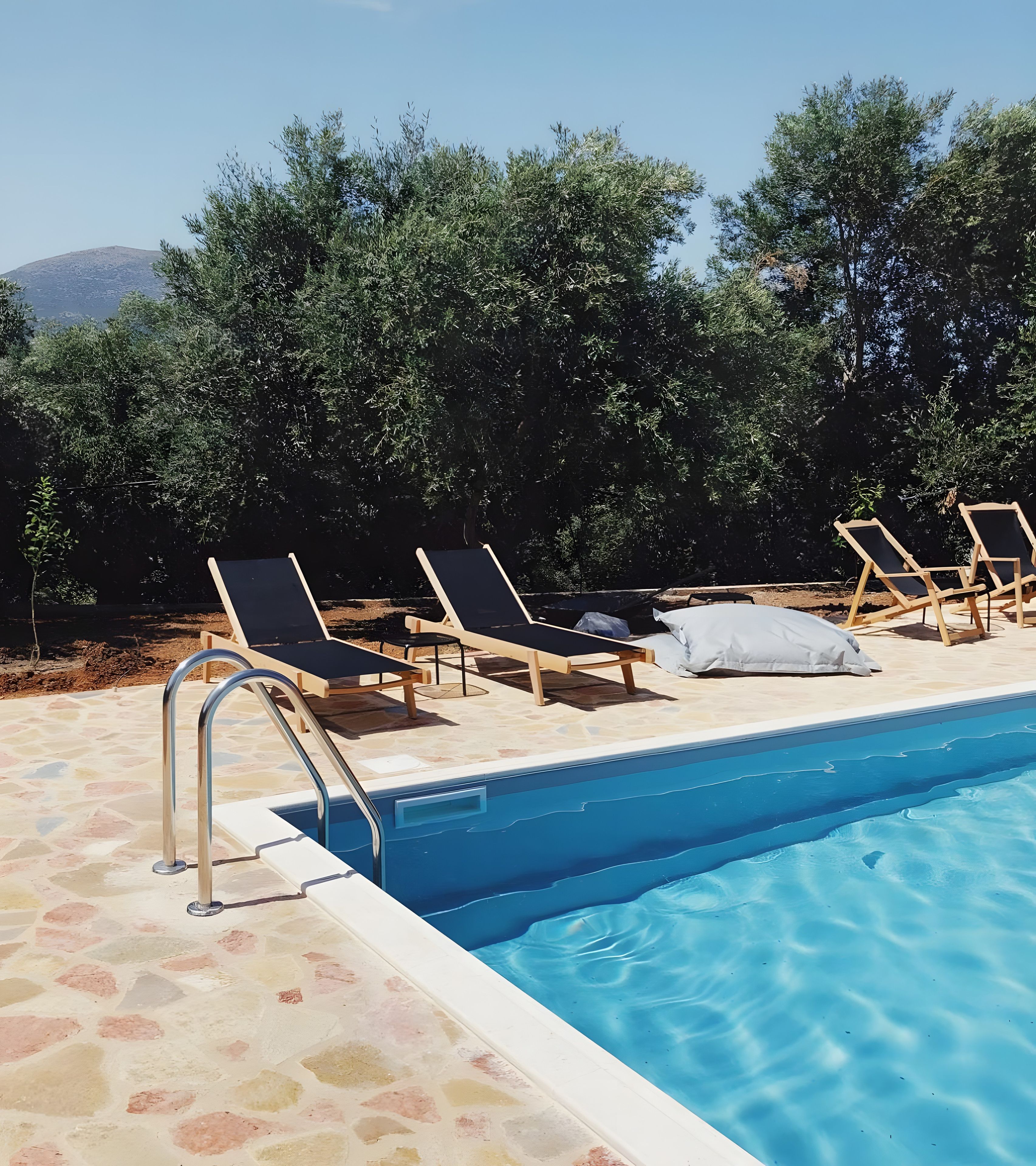 A swimming pool with lounge chairs and a stone deck.