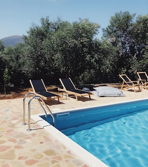 A swimming pool with lounge chairs and a stone deck. - Villa Gaia - Private Pool Villa in Monemvasia (Άγιος Στέφανος)