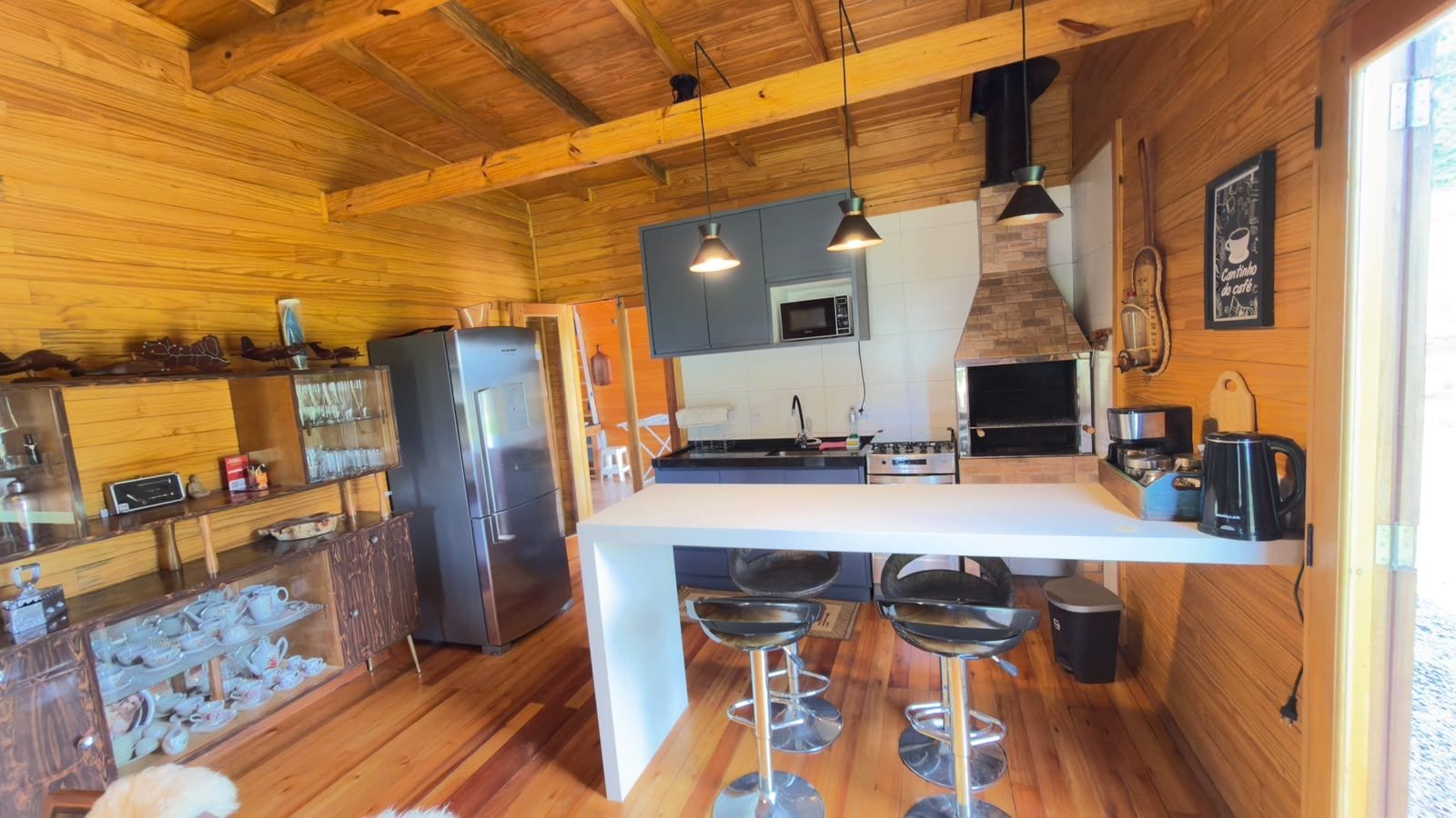 A compact kitchen with a central island, bar stools, and a wooden ceiling.
