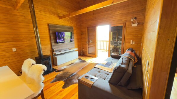 A log cabin interior with a sofa, television, and a fireplace. - Casa Blue Sunset (Urubici)