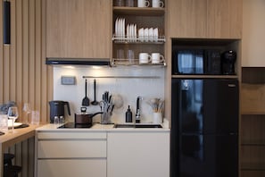 A modern kitchen with a Bosch range hood, a Haier refrigerator, and a coffee maker on the countertop. - Mountain View Corner Unit in Laguna with Rooftop Pool & 10min-walk to the Beach (ตำบลเชิงทะเล)