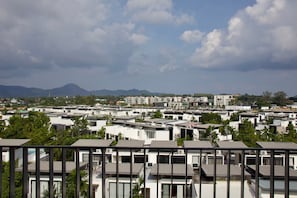 A residential area with modern buildings, a clear sky, and distant mountains. - Mountain View Corner Unit in Laguna with Rooftop Pool & 10min-walk to the Beach (ตำบลเชิงทะเล)