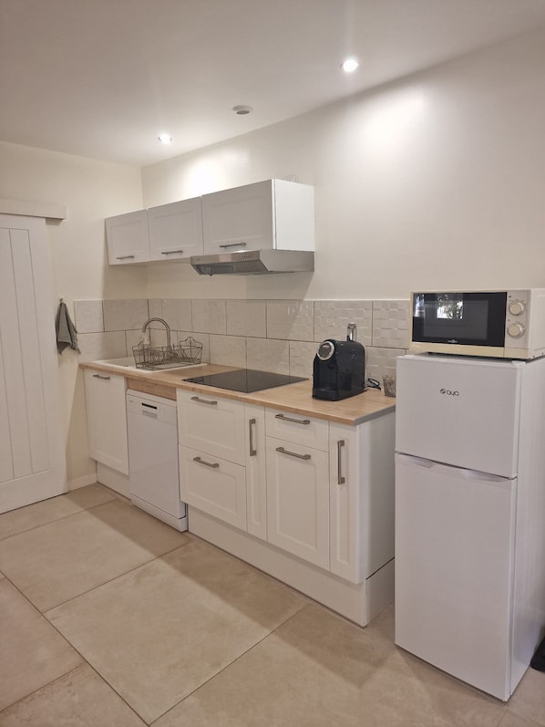 A modern kitchen with white cabinets, a built-in microwave, and a coffee maker.