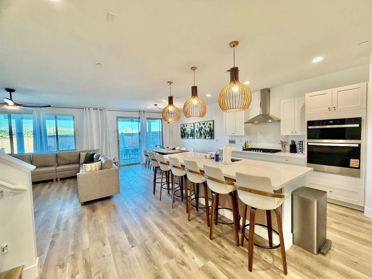 A modern kitchen with a central island, bar stools, and a dining area with a sofa.