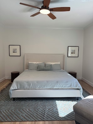 A bedroom with a bed, a ceiling fan, two bedside tables, and two framed pictures on the walls. - Dream home in Acworth - Pool and close to Lakepoint (Acworth)