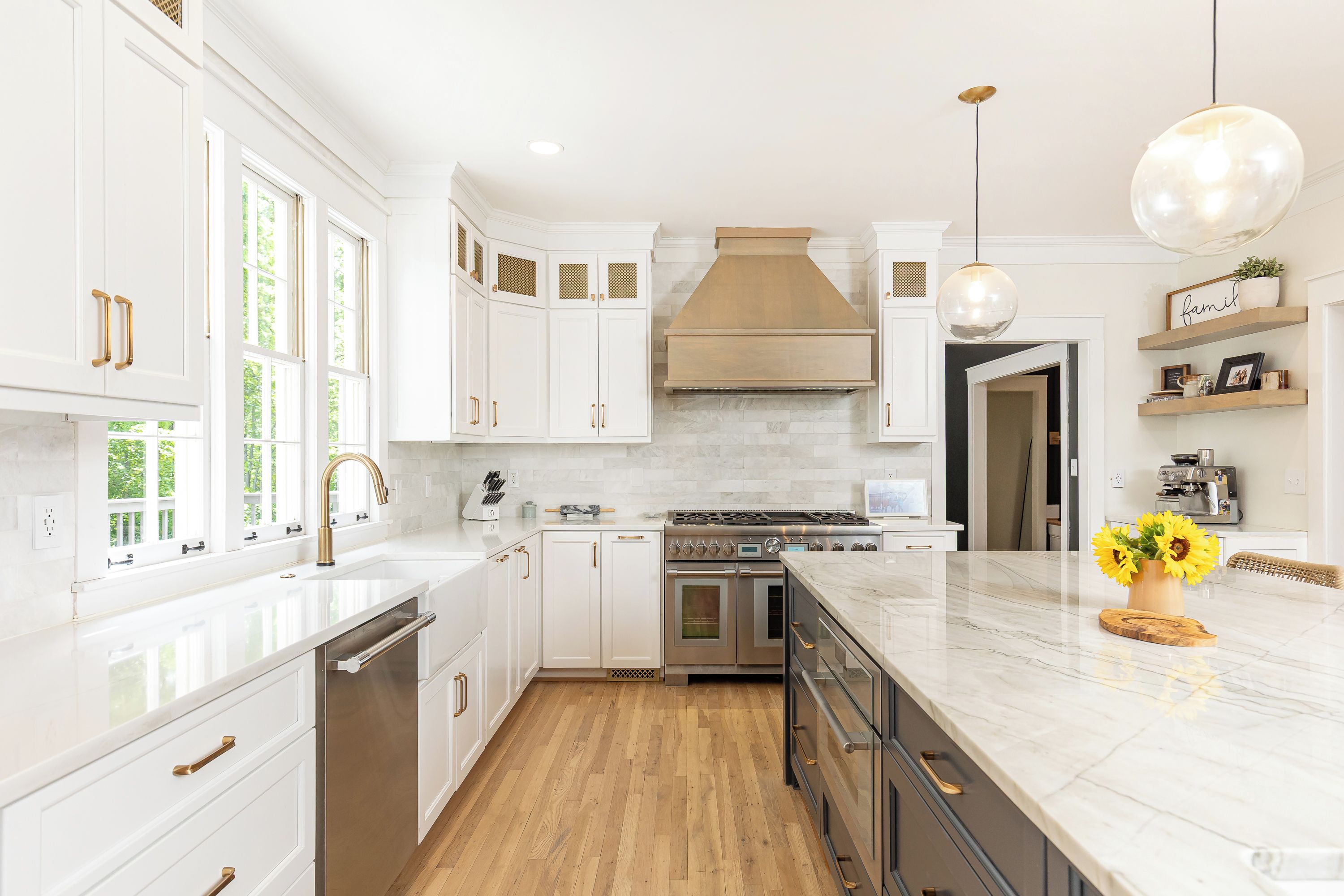 A modern kitchen with white cabinetry, a stainless steel range, and a wooden floor.