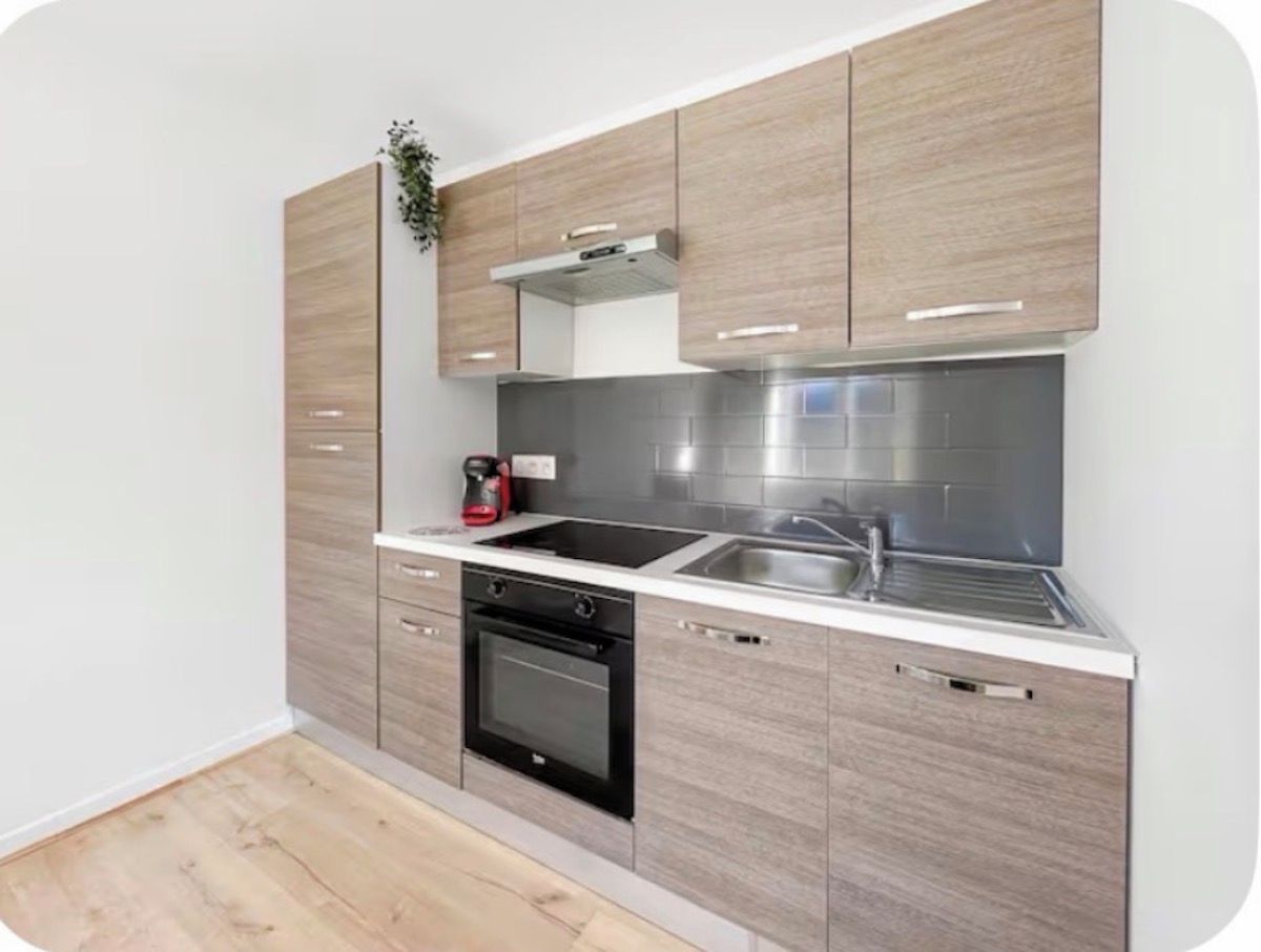 Una cocina moderna con horno integrado, estufa y lavamanos.