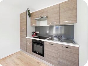 Een moderne keuken met een inbouwoven, een kookplaat en een spoelbak.