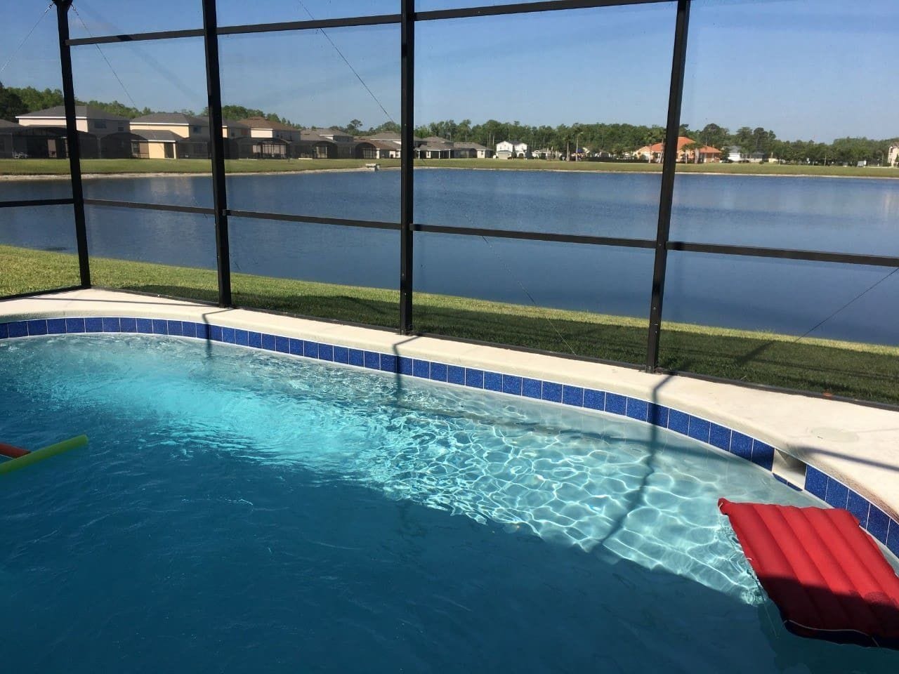 A swimming pool with a view of a lake and houses in the background.