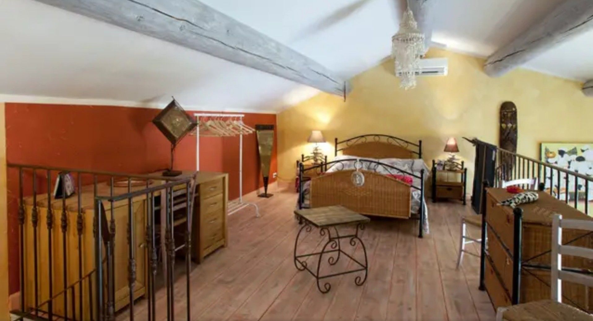 Ein Schlafzimmer mit einem Bett, Nachttischen, einer Kommode und einer Treppe.