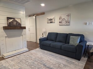 A living room with a dark blue sofa, a white door, and two wall-mounted paintings.