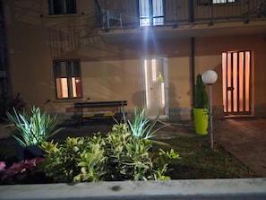 Un bâtiment doté d’un balcon, d’un banc, d’une porte et d’une plante en pot.
