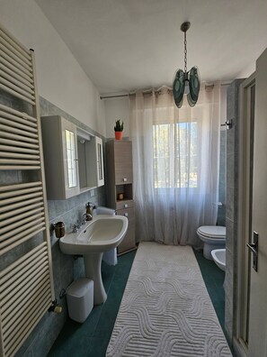 Une salle de bain équipée d’un lavabo, d’un miroir, d’un porte-serviettes, de toilettes et d’un espace douche.