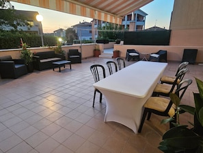 Un espace extérieur aménagé en terrasse, avec une table à manger, des chaises, des canapés et des plantes en pot.