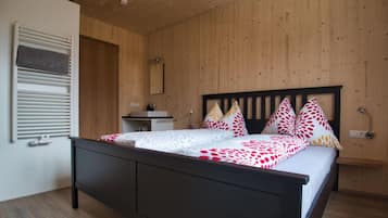 Ein Schlafzimmer mit Holzboden, einem Bett mit schwarzem Gestell, einem Nachttisch und einem Spiegel.