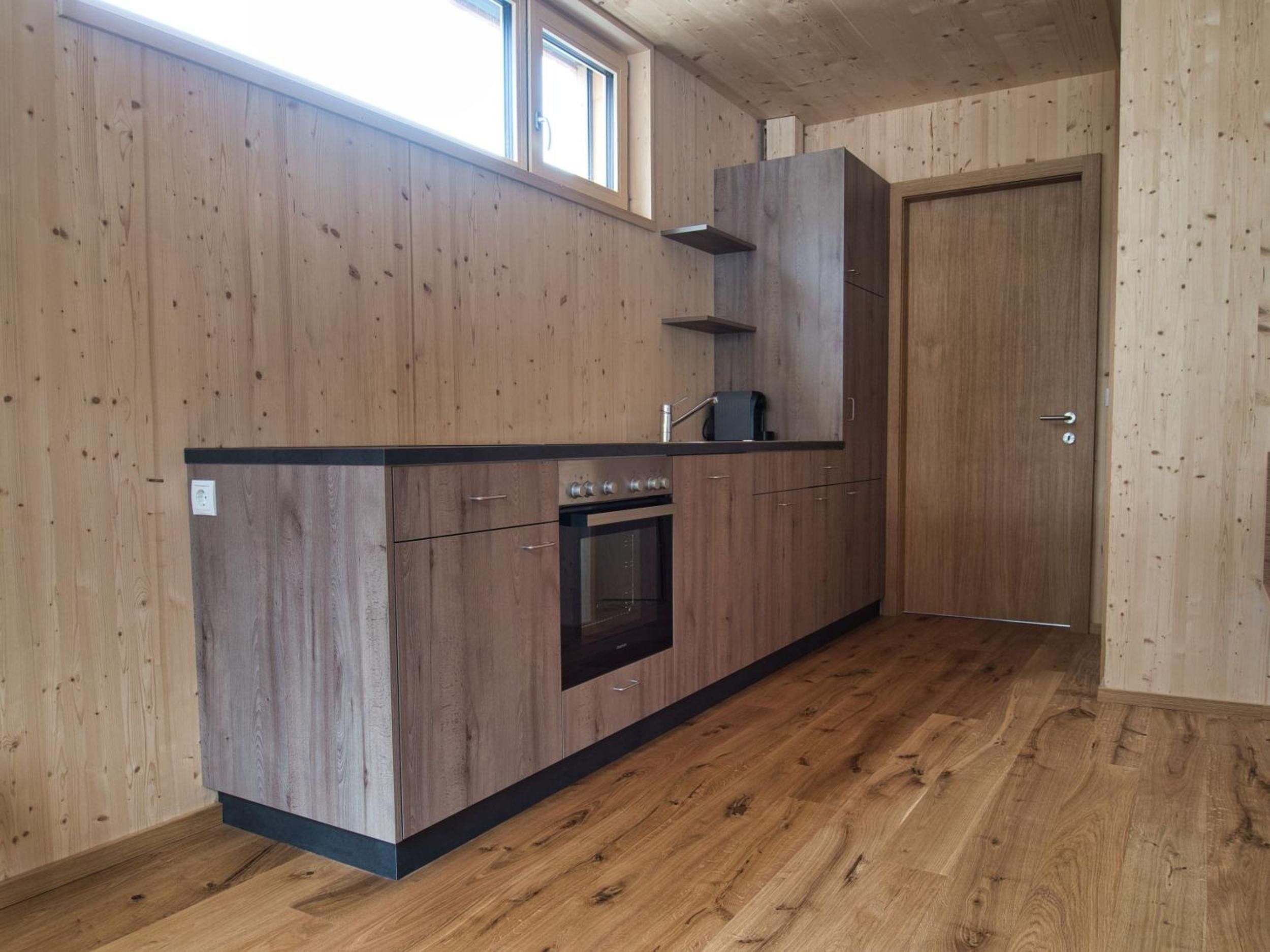 Eine Küche mit Holzausstattung, einem eingebauten Backofen und einem Fenster über der Spüle.