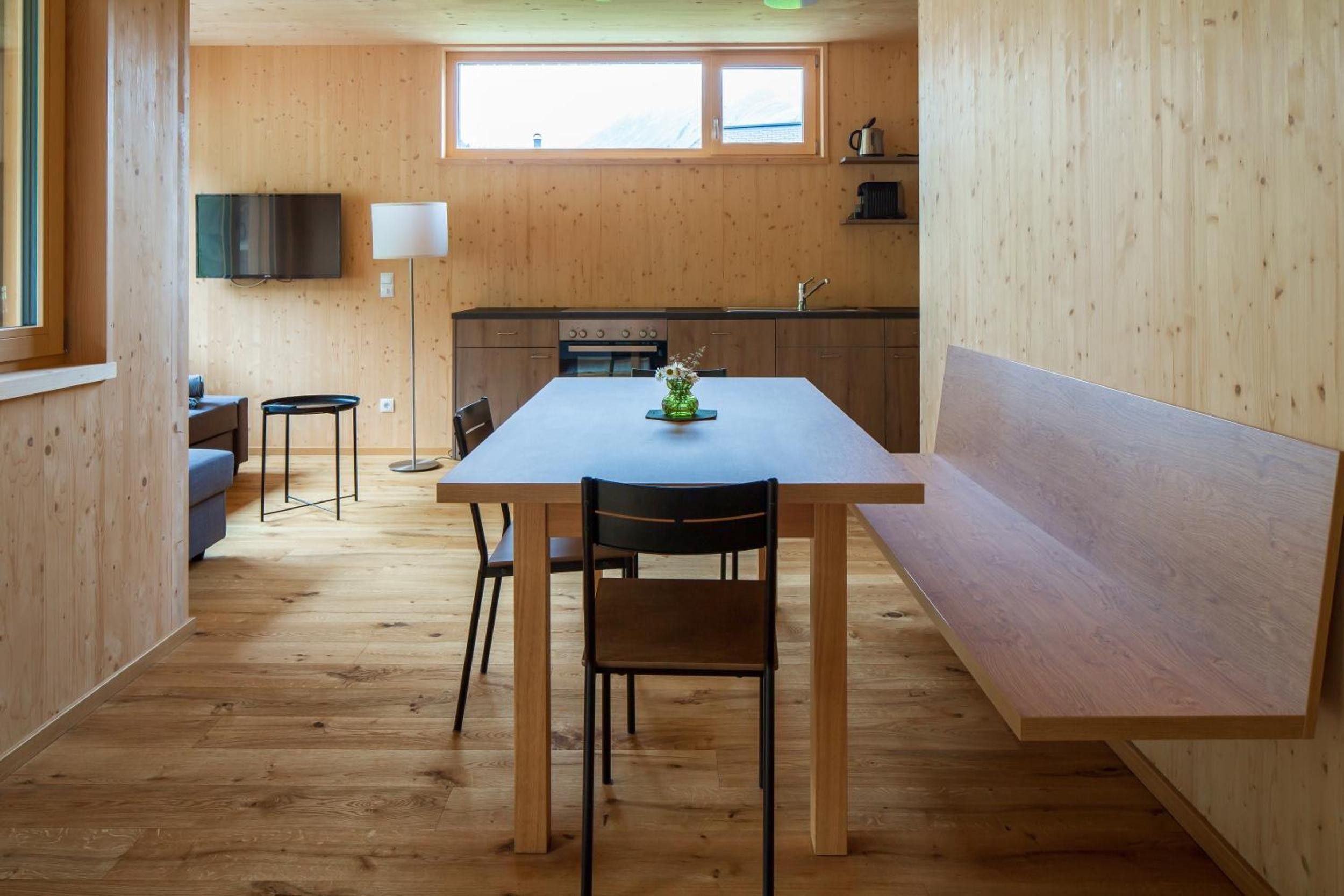 Eine kleine Küche mit Holzwänden, einem Esstisch und einer Couch.