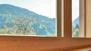 Ein hölzernes Fenster mit Blick auf eine bewaldete Bergkette.