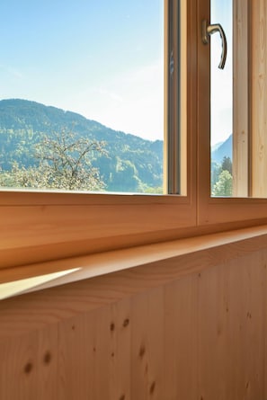 Ein hölzernes Fenster mit Blick auf eine bewaldete Bergkette.