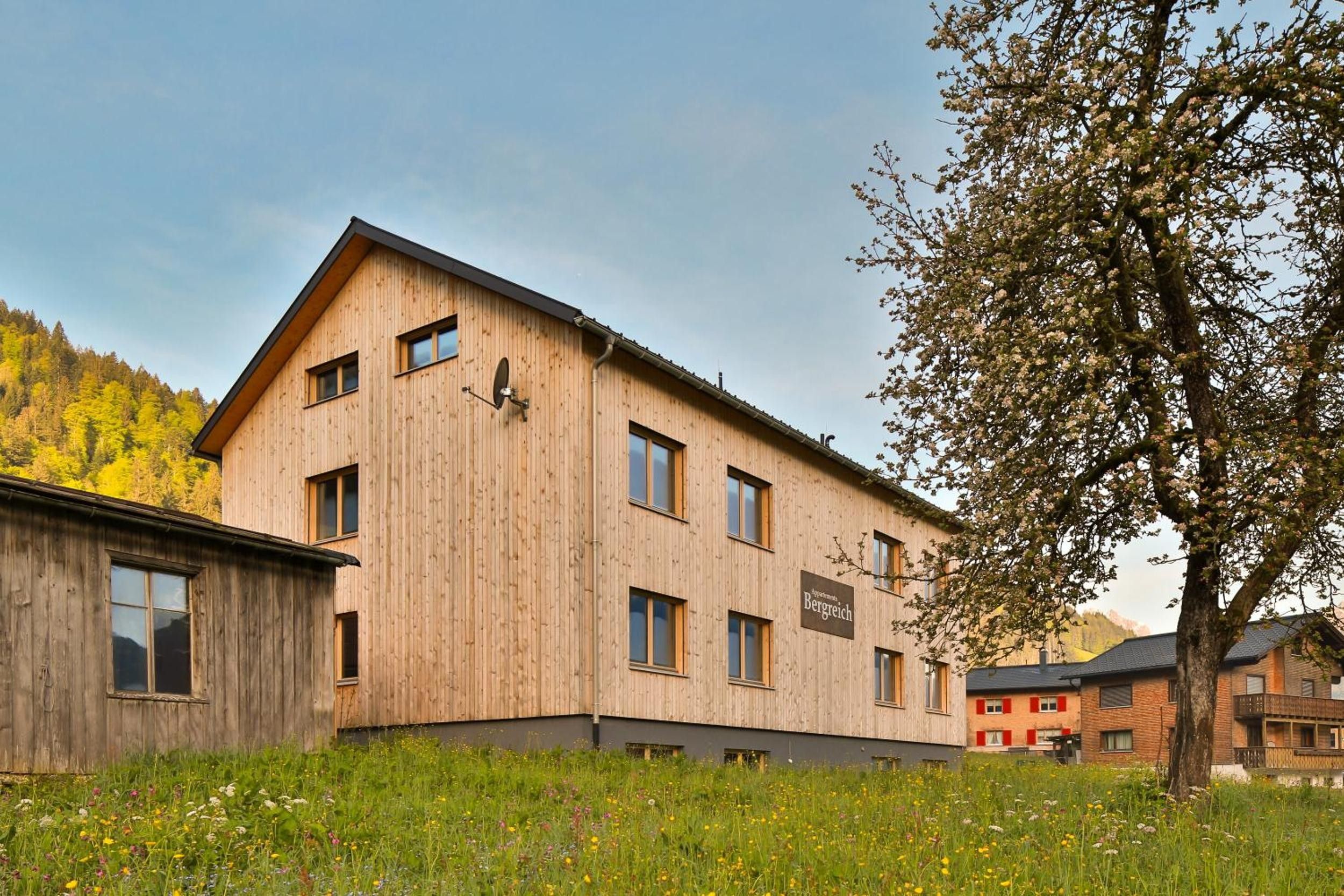 Ein mehrstöckiges Holzgebäude mit zahlreichen Fenstern und einem Schild, das es als Gästehaus kennzeichnet.